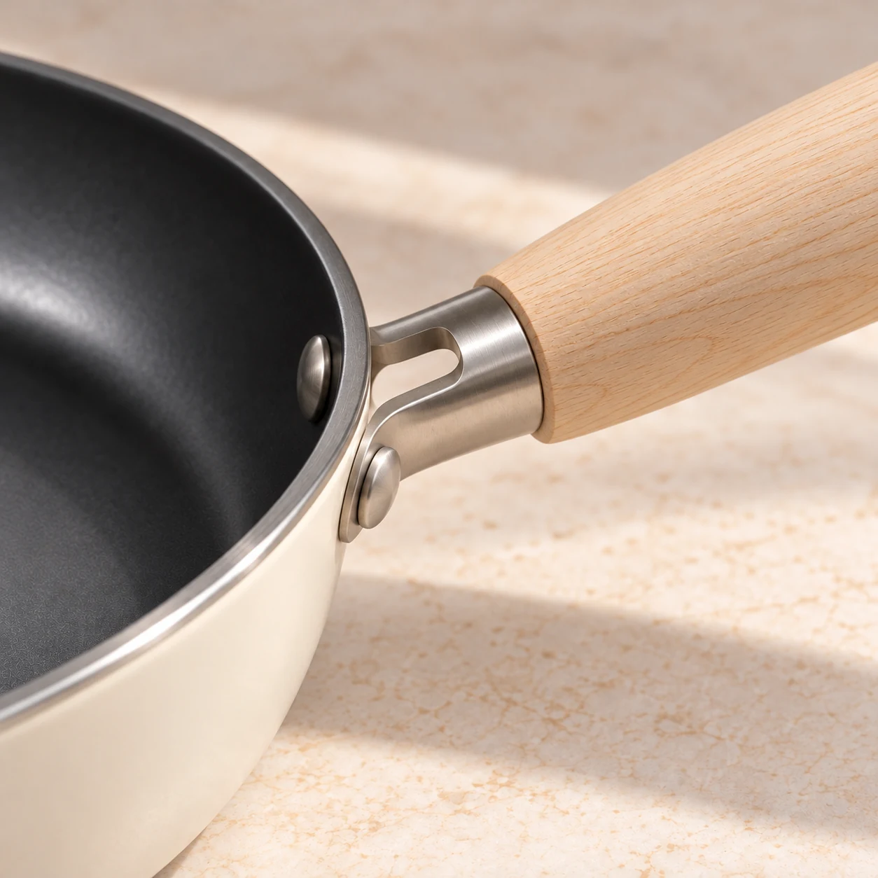 Close view of the pale wood handle, open steel connector, ivory exterior and charcoal interior